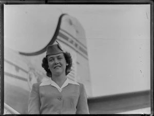 Portrait of PAA Stewardess Dorothy Hand in front of PAA Clipper Oriental NC 88957 passenger plane, [Whenuapai Airfield, Auckland?]