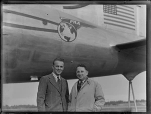 Portrait of Mr Eric Nyland and Mr Borum of Turners and Growers in front of PAA Clipper Oriental NC 88957 passenger plane, [Whenuapai Airfield, Auckland?]