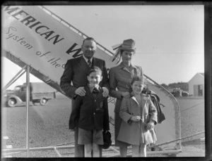 Portrait of PAA passenger Mr and Mrs Naismith in front of aeroplane boarding steps, [Whenuapai Airfield, Auckland?]