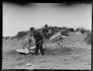 Goldmining, view of 'pioneer beachcombers' Bell and Ted Bagley panning for gold using a sluice box on a South Westland beach, West Coast Region