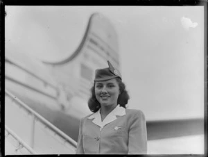 Portrait of PAA Stewardess Patricia Meek in front of PAA Clipper Celestial NC 88959 passenger plane, Whenuapai Airfield, Auckland