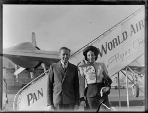Portrait of PAA passenger arrivals Mr and Mrs Yock in front of boarding steps, [Whenuapai Airfield, Auckland?]