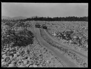 Goldmining, view of two touring cars on a shingle road through gold mining tailings, West Coast Region