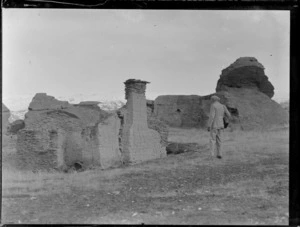 Goldmining, view an unidentified man looking at the remains of an old gold miner's high country house, Central Otago region