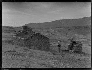 Goldmining, view an unidentified man looking at the remains of an old gold miner's high country house, Central Otago Region