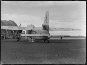 Tail view of visiting Bristol Freighter transport plane 'Merchant Venturer' G-AIMC with unidentified men beyond, Whenuapai Airfield, Auckland