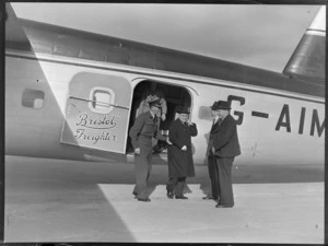 View of Mr T O'Connell in uniform and Mr J A C Allum (Mayor of Auckland) with unidentified men viewing visiting Bristol Freighter transport plane 'Merchant Venturer' G-AIMC with side cargo doors open, Whenuapai Airfield, Auckland