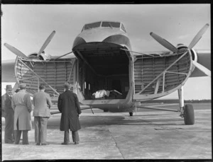 View of front cargo doors open of visiting Bristol Freighter transport plane 'Merchant Venturer' G-AIMC with unidentified men looking on, Whenuapai Airfield, Auckland City