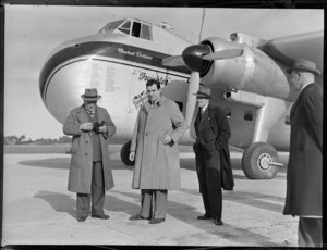 View of (L to R) Mr Shorter (senior) with camera, Mr E Shorter and Mr Barker (NZR) and an unidentified man in front of visiting Bristol Freighter transport plane 'Merchant Venturer' G-AIMC, Whenuapai Airfield, Auckland City