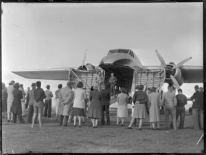 Two unidentified men standing inside a Bristol Freighter aircraft, speaking to a crowd of people, Kaikohe