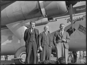Mr R A Phillpotts (Bank of New South Wales) (from left), N McDonald (Kaikohe Hotel) and L Mehrtens (Bank of New Zealand), beside a Bristol Freighter 'Merchant Venturer' aircraft, including a dog in the foreground