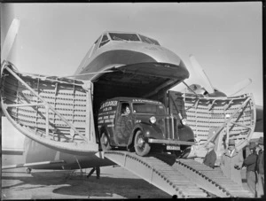 Unidentified man inside a J B O'Loghlen and Company Limited truck, driving off a Bristol Freighter aircraft, Kaikohe