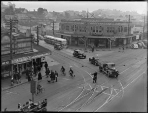 Wakefield Castrol Oil photographs, showing corner street scene in Newmarket, Auckland, including shops, buses, motorcars and boys on bicycles