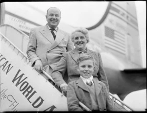 Hodges family, including a young boy, on arrival and standing on a gangway in front of a PAA (Pan American Airways) Clipper Kathay NC88883 aircraft, location unidentified