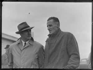 Portrait of (L to R) J B O'Loghlen and Mr Baker of NZ Railways awaiting the arrival of Bristol Freighter 'Merchant Venturer' G-AIMC transport plane, Whenuapai Airfield, Auckland