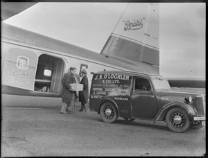 View of unidentified men loading a box into the back of a J B O'Loghlen truck from an open side door of the Bristol Freighter transport plane 'Merchant Venturer' G-AIMC, Whenuapai Airfield, Auckland