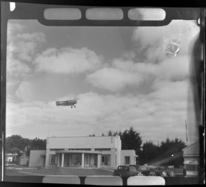A Rearwin Sportster aeroplane in flight over the clubrooms at the Auckland Aero Club