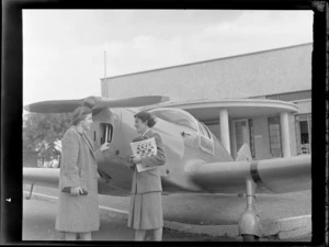 Mrs K Robinson, left, and Mrs Exton, with a Tiger Moth aeroplane, in front of clubrooms at Auckland Aero Club, Mangere, Auckland