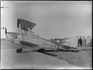 Unidentified group of men and women viewing Tiger Moth aircraft KZK-ANE