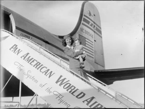 Air hostess, P Greaney holding unidentified baby, departing Pan American World Airway NC88944, Clipper Express aircraft