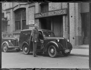 View of Lloyd Thomas bidding farewell to his 'cobbers', getting into a Whites Aviation Ltd van in front of Darby's Building with H & M Thorburn Ltd Coats and J M Mahon Printers, Auckland City