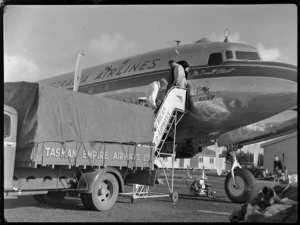 Airport ground crew loading freight on to aircraft McDouall Stuart, TAA (Trans Australia Airlines), at Whenuapai Air Base, Auckland