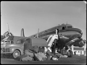 Airport ground crew unloading mail and freight from aircraft McDouall Stuart, TAA (Trans Australia Airlines), at Whenuapai Air Base, Auckland