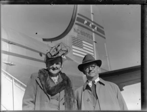Portrait of Mrs Edna Craig and Mr Stanley Craig in front of PAWA Clipper Celestial NC 88959 passenger plane, Whenuapai Airfield, Auckland