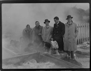 Guide Rangi (left), Captain Ellison, Mr W R Burns, Mr F E Sander and Mr J Lansdale of Bristol Freighter Tour, including children bathing in thermal pool, Rotorua, Bay of Plenty
