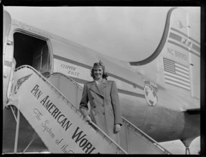 Unidentified air stewardess, next to aircraft Douglas DC-4 Clipper Racer, PAWA (Pan America World Airways), unidentified location