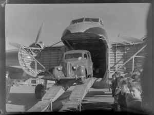 Bristol Freighter Tour, view of an unidentified man unloading a car off Bristol Freighter transport plane 'Merchant Venturer' G-AIMC with children looking on, Harewood Airport, Christchurch City