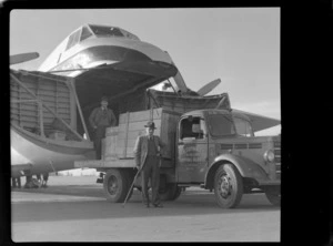 Bristol Freighter Tour, view of freight being loaded into the cargo bay of Bristol Freighter transport plane 'Merchant Venturer' G-AIMC from an A R Guthrey & Co Ltd truck with A R Guthrey in front, Harewood Airport, Christchurch City