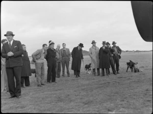 Group of unidentified men and dogs, during Bristol Freighter transport aeroplane tour, at Paraparaumu Aiport, Kapiti Coast District