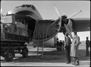 Mr I Thomas (Administration Assistant, New Zealand Railways Department), and Mr CC Brice (Station Master, Blenheim), standing alongside Bristol Freighter transport aeroplane 'Merchant Venturer', which is being loaded with cargo from a 'NZR Road Services' truck, Woodbourne, Marlborough District