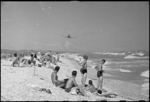 New Zealanders from Rest Camp near Ancona, Italy, watch Allied aeroplane flying over beach on Adriatic Sea, World War II - Photograph taken by George Kaye