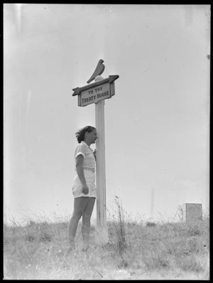 Unidentified woman standing under sign to Waitangi Treaty House
