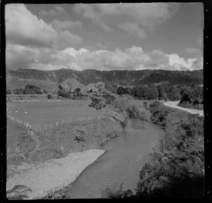 View of an unidentified river and road with farmland and native forest covered hills beyond, Mahoenui district, Waikato Region