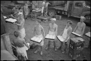 Members of the 2 New Zealand Field Bakery form a chain to pass loaves for baking in the oven, Italy, World War II - Photograph taken by George Kaye