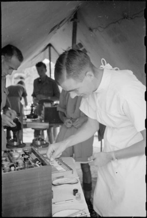 Captain W Simmers selects dental instrument at New Zealand Mobile Dental Unit Headquarters in Italy, World War II - Photograph taken by George Kaye