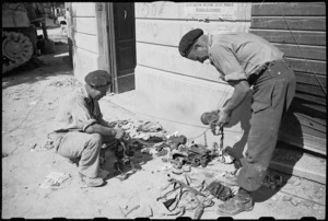 W Dixie and B Gray examining gear abandoned by enemy troops in Rimini, Italy, World War II - Photograph taken by George Kaye