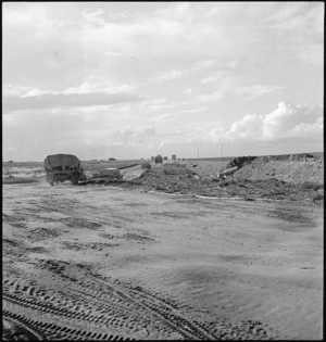 World War II transport bypassing demolished bridge travels past taped track through minefield near Sirte, Libya