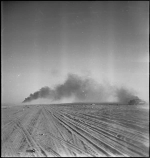 Smoke from burning Italian tanks drifts across 8th Army vehicle tracks at Wadi ZemZem, Libya - Photograph taken by H Paton