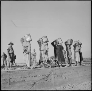 Local workers carrying concrete during road making in Trans Jordania, World War II - Photograph taken by M D Elias