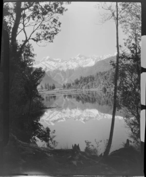 Lake Matheson, includes unidentified man in boat and Mount Aoraki/Cook in backgound, West Coast Region