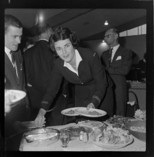 Unidentified woman in uniform filling two plates from the buffet table at a function for British Oversea Airways Corporation