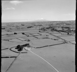 View of farmland with a farmhouse and road to Mount Taranaki beyond, Waverley District, South Taranaki Region