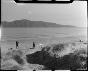 Two unidentified young men on Paraparaumu Beach, looking toward Kapiti Island