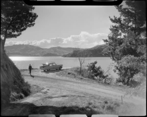 Akaroa, Banks Peninsula, including unidentified young man with his motorcar on a road, looking out to the harbour