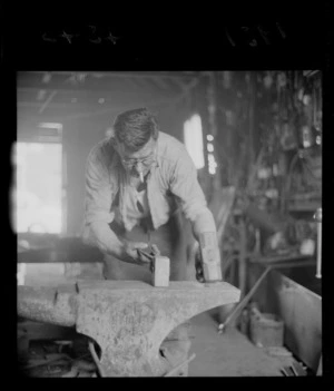 Unidentified blacksmith working at an anvil, in a workshop, Johnsonville, Wellington