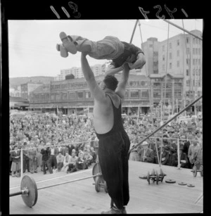 Weightlifter Hugh Jones lifting a man during a demonstration in Civic Square, Wellington